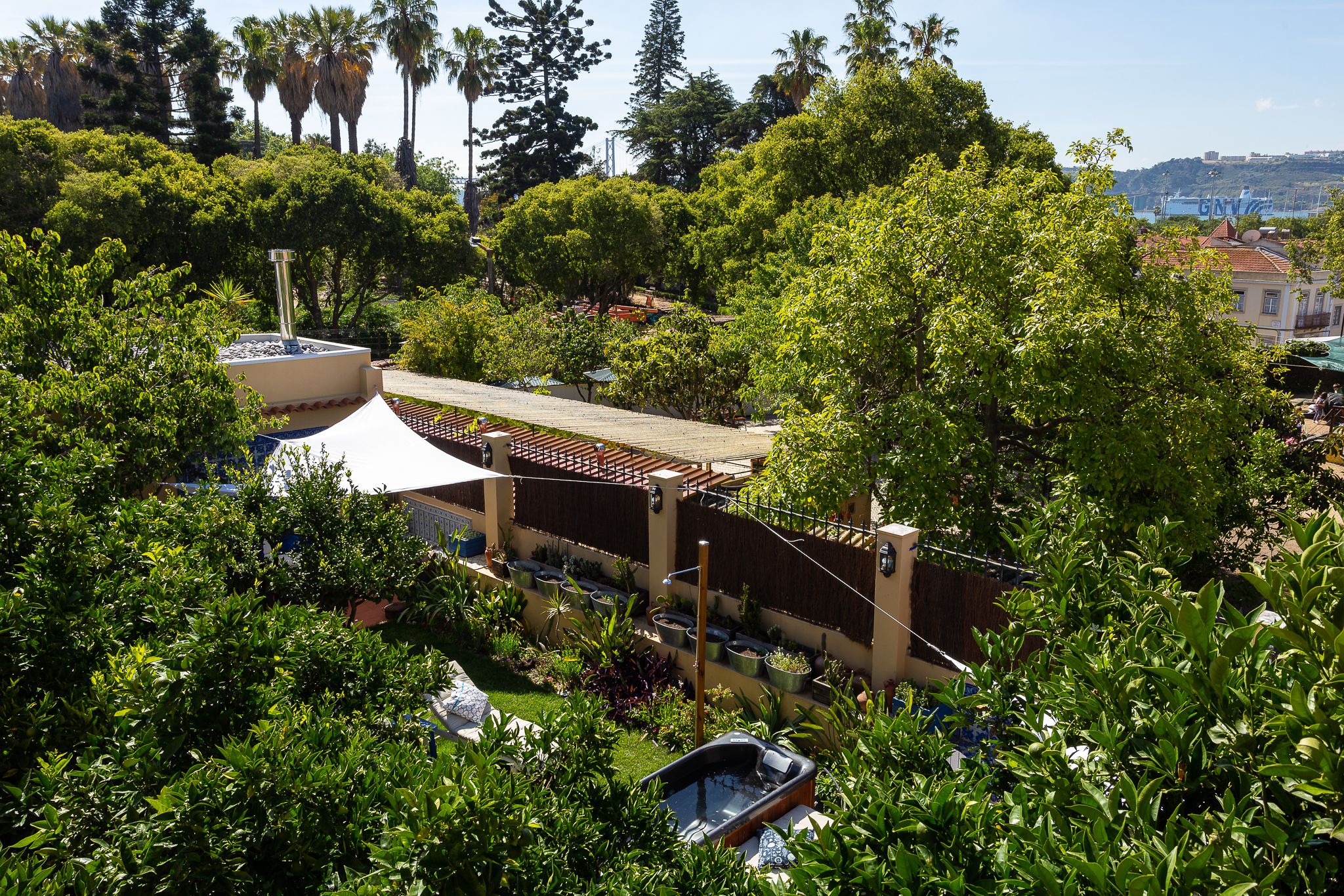Un jardin luxuriant agrémenté d’une pergola, d’un jacuzzi et d’une tente blanche.
