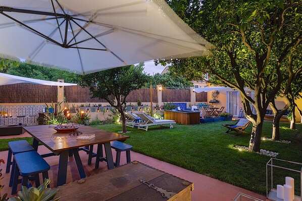An outdoor patio area with a wooden table, blue chairs, and a large umbrella.