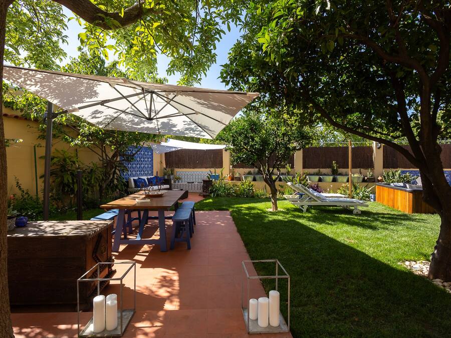 Un patio al aire libre con una mesa, sillas y una sombrilla grande.