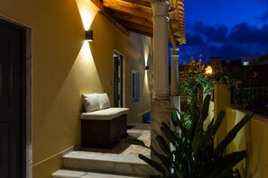 A well-lit outdoor area with a bench, a column, and a door leading to another room.