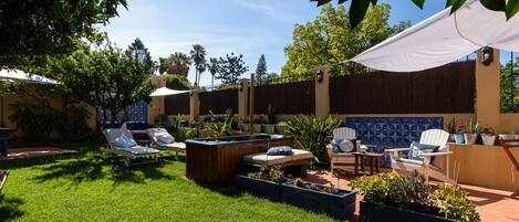 Un patio con sillones de descanso, una jardinera de madera y un muro de baldosas.