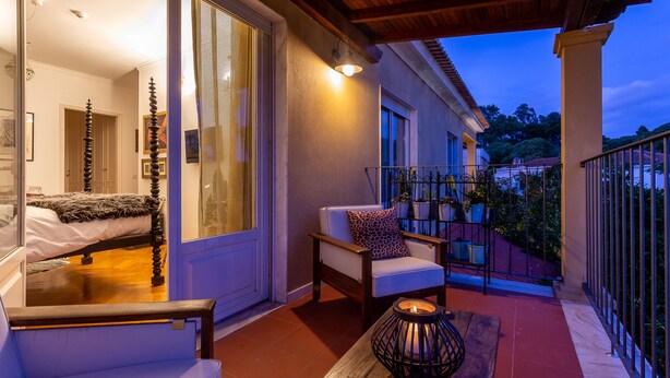 A bedroom with a large window, a bed, and a chair with a cushion. - Geronimo Guest House Belém (Lisbon)