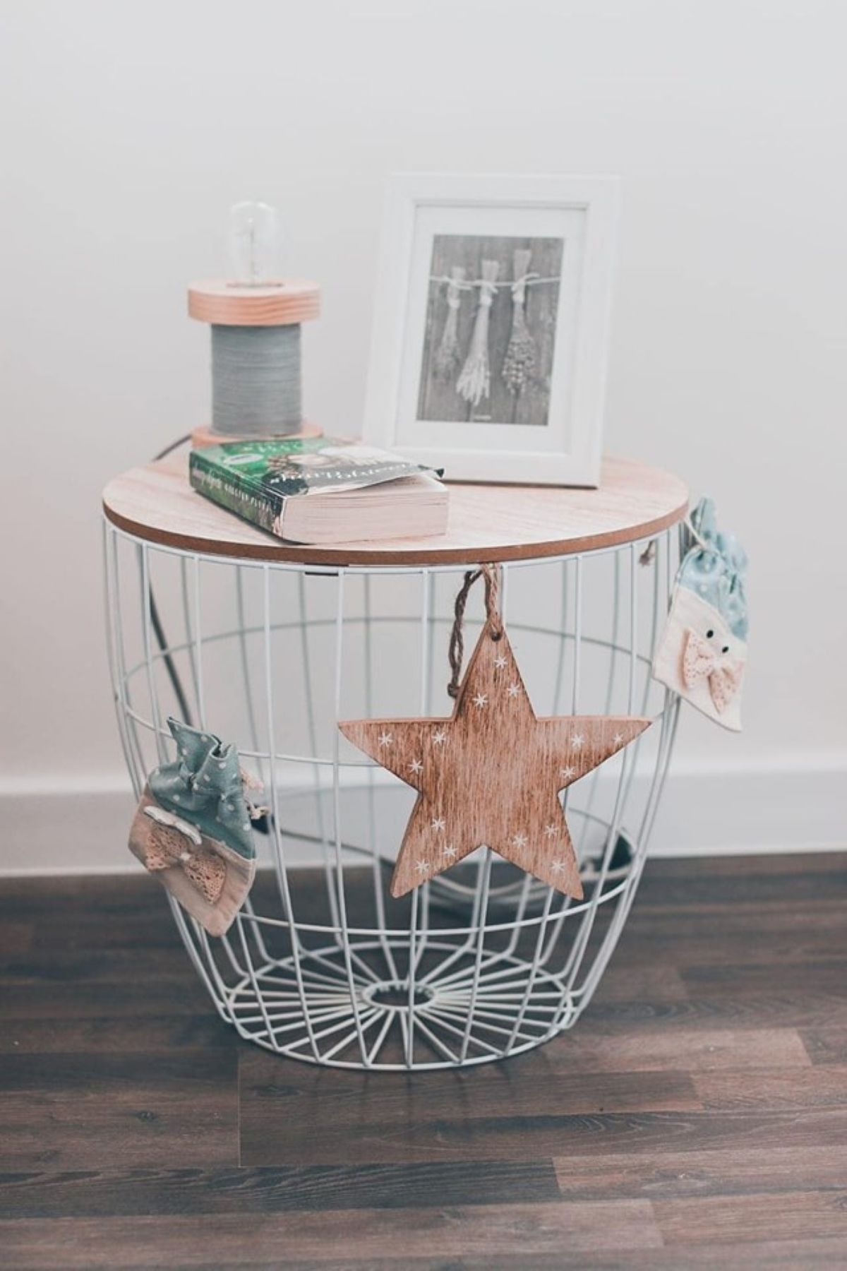 A round metal wire table with a wooden top, a framed picture, and a star decoration.