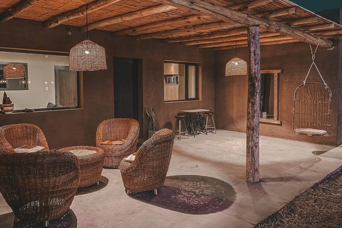 Un espace extérieur aménagé avec des meubles en osier et des luminaires suspendus.
