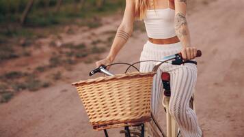 A person riding a bicycle with a basket on a dirt path.