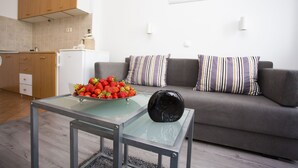 Una sala de estar moderna con una mesa de centro de vidrio, un sofá gris y un tazón de fresas.