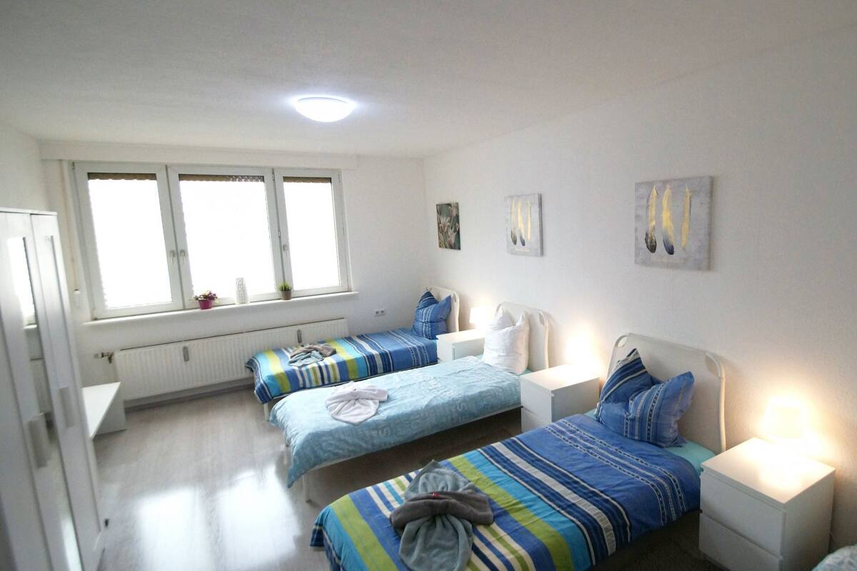 A room with two beds, a radiator, a window, and wall art.