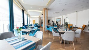 A modern hotel lobby with a mix of seating areas, a reception desk, and a view of the city. - INTERFERIE Cechsztyn w Ustroniu Morskim (Ustronie Morskie)