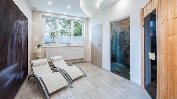A modern spa room with a large window, a wall-mounted waterfall, and two reclining chairs. - INTERFERIE Cechsztyn w Ustroniu Morskim (Ustronie Morskie)