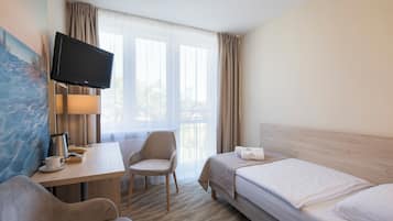 Habitación de hotel con cama, escritorio con televisor, una silla y un cuadro en la pared.