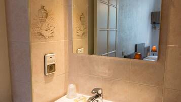 A bathroom with a white sink, a mirror, and a towel dispenser.
