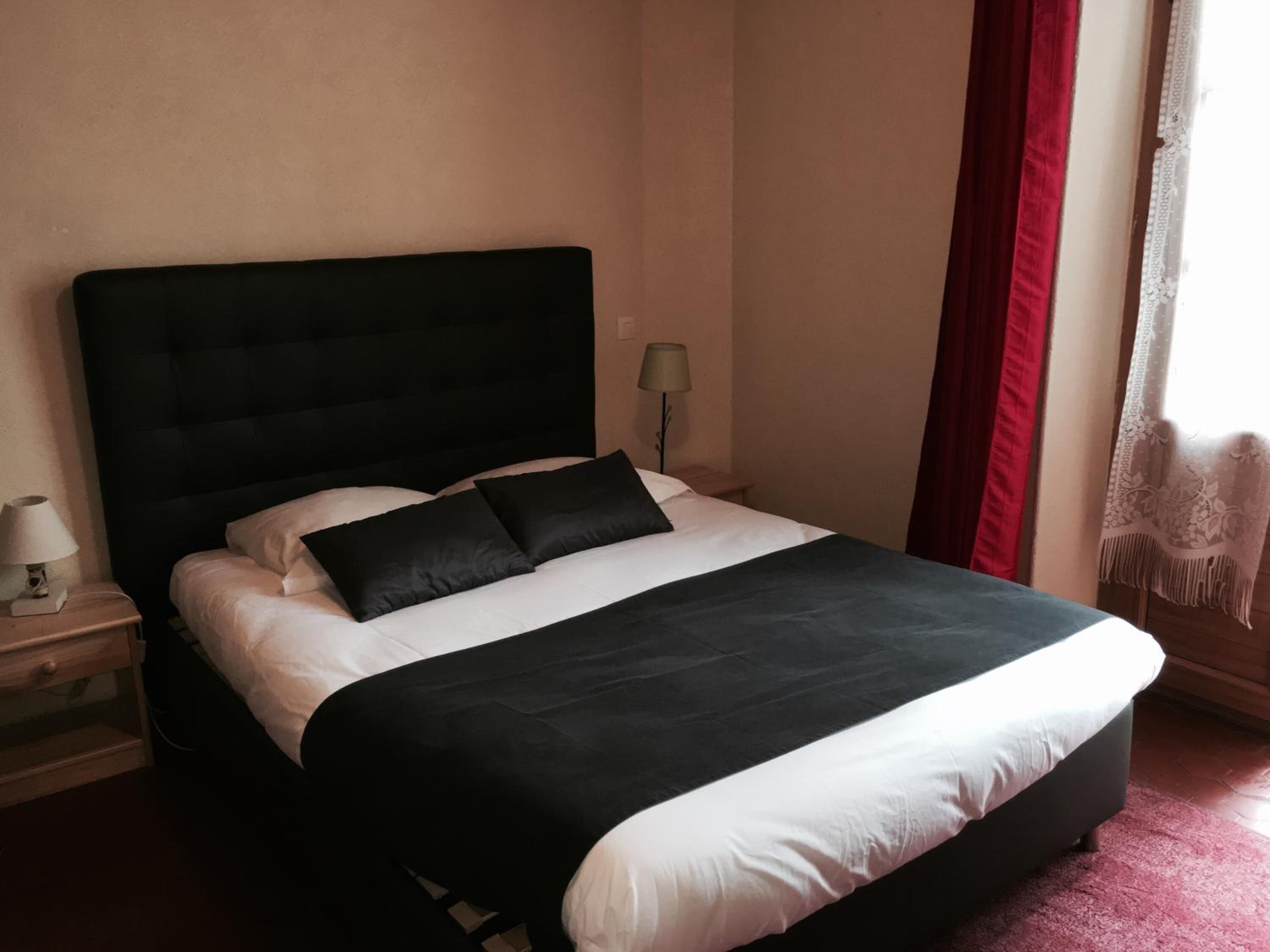 Una cama bien hecha con cabecera negra, ropa de cama blanca y dos almohadas negras.