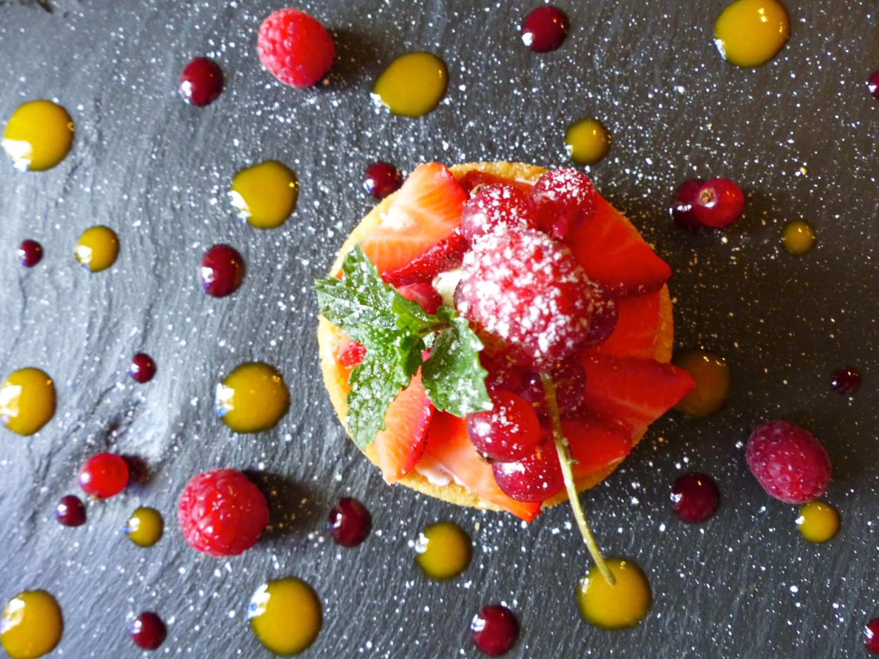 A dessert with fruit and mint on a slate surface.
