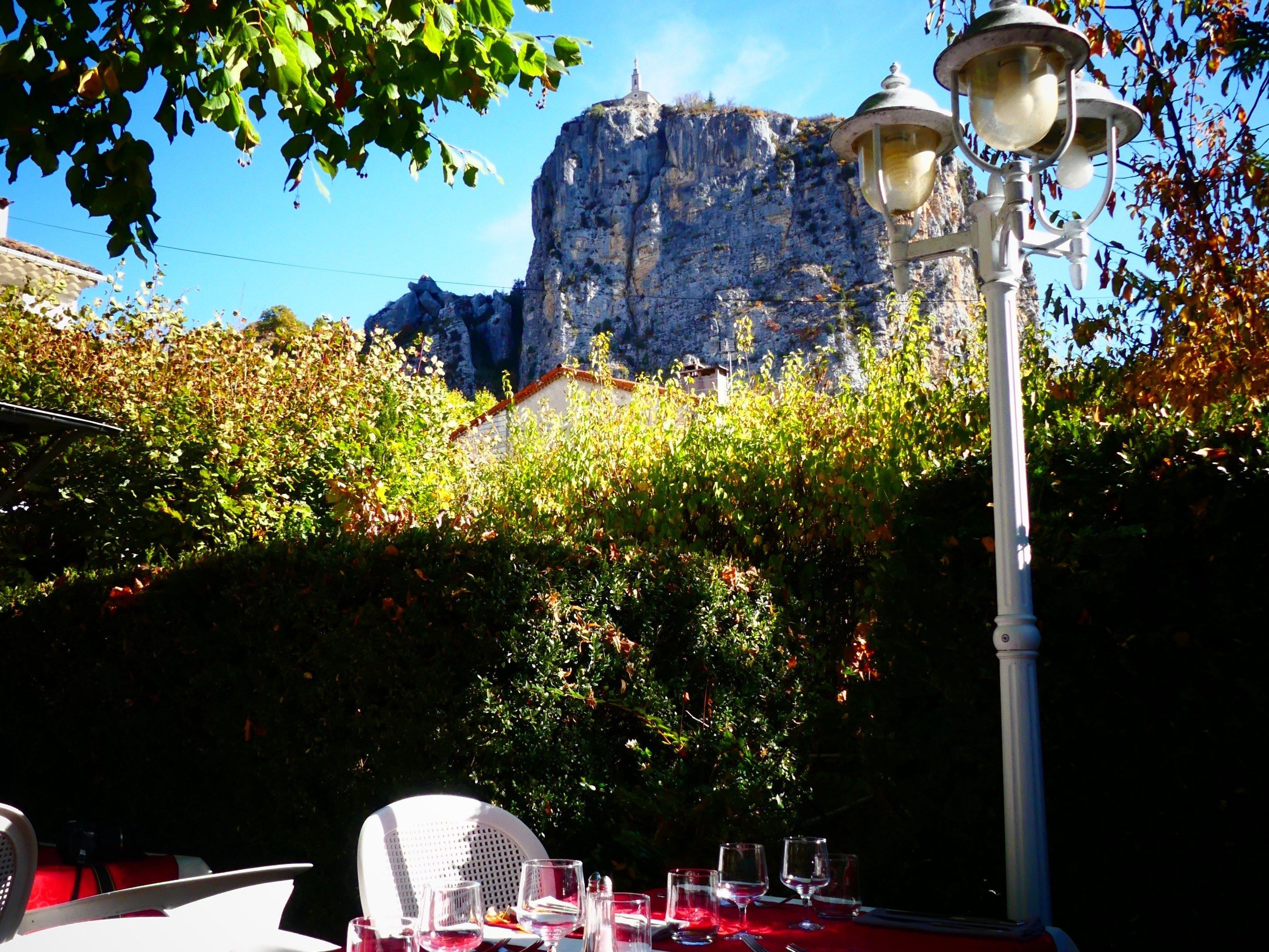 Un espace de restauration en plein air avec une table dressée pour deux personnes, un lampadaire et une montagne en arrière-plan.