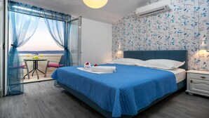 Un dormitorio con una cama grande, una mesita de noche, cortinas de gasa y vistas al exterior.