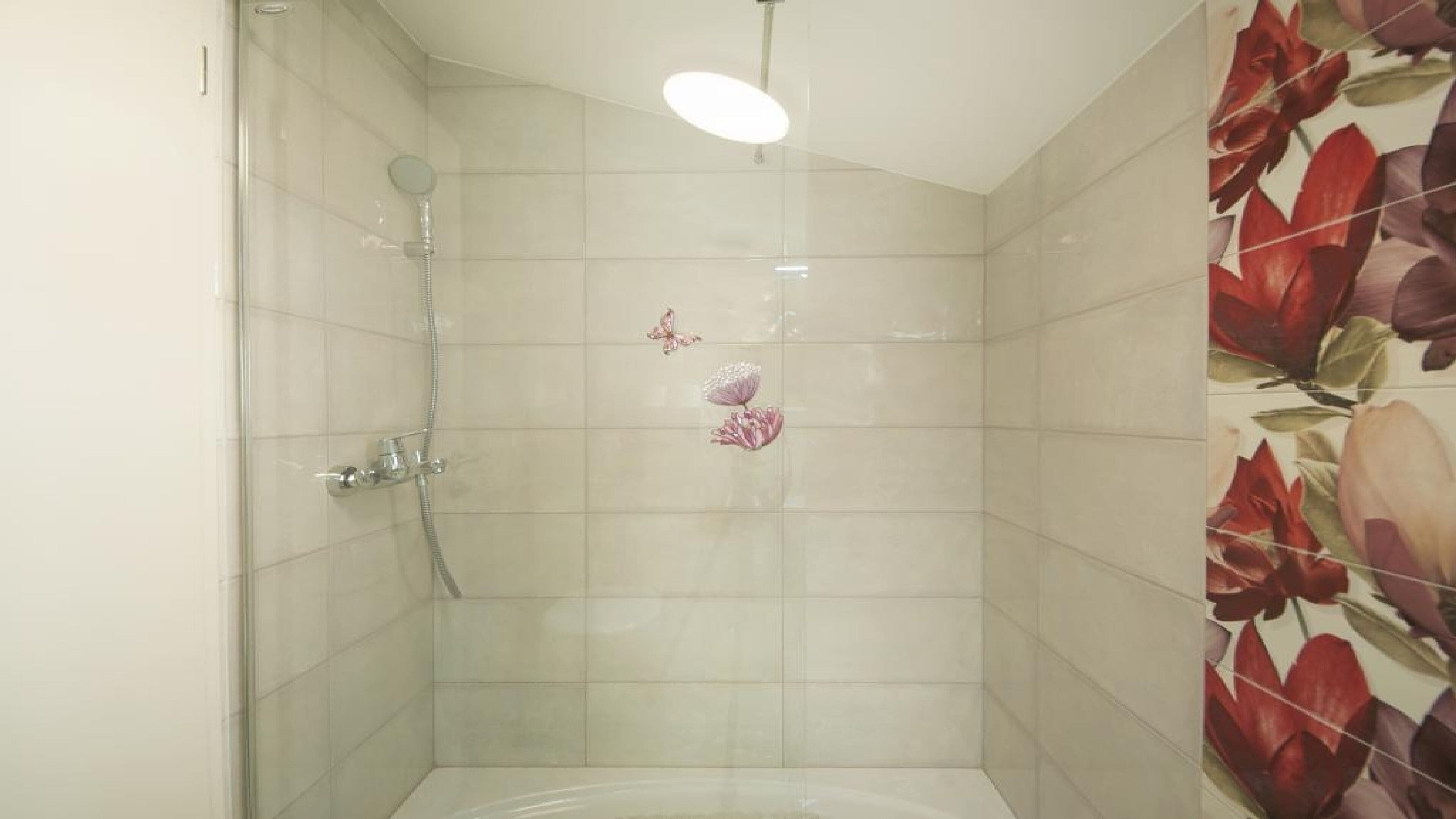 Een douche met een handdouche en een kraan op de muur.