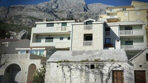 Una hilera de edificios de varios pisos con balcones, con montañas al fondo.