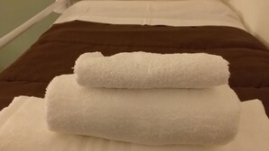 A single bed with white and brown bedding, a white pillow, and a white wall with a small shelf. - Hostel alexander (Naples)
