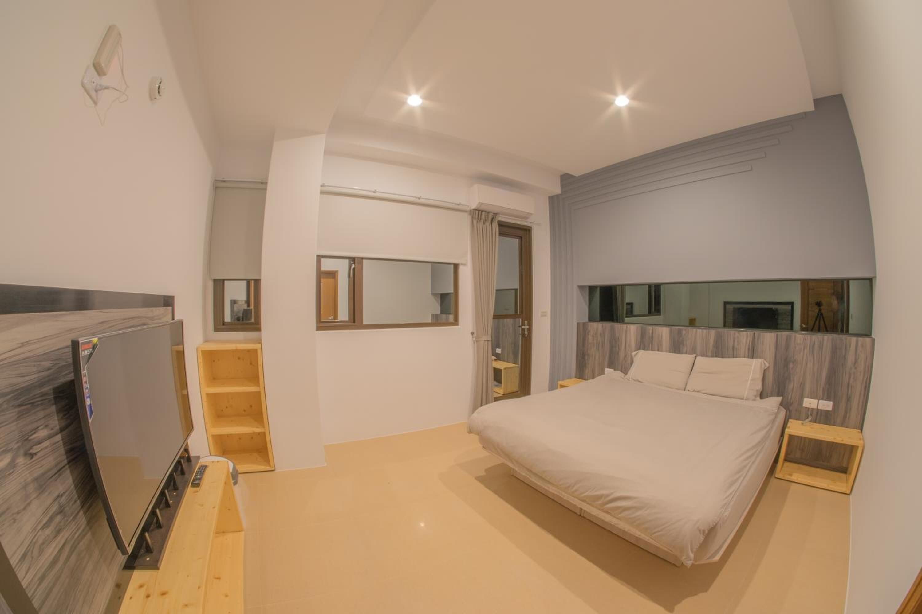 A modern bedroom with a large bed, a TV, and a wooden staircase.