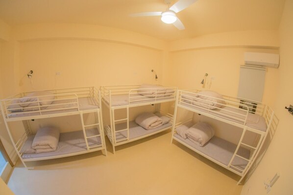 A room with three bunk beds, a ceiling fan, and an air conditioning unit.