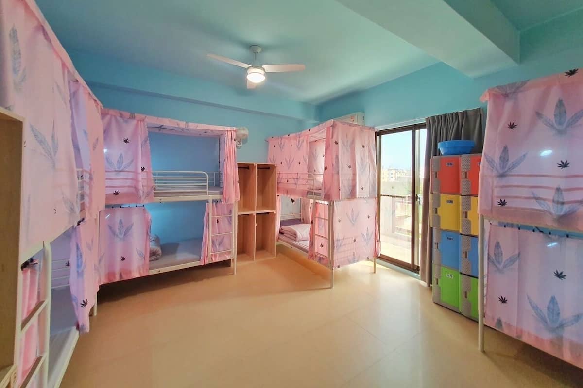 A room with bunk beds covered in floral-patterned bedding, a ceiling fan, and a view through a glass door.
