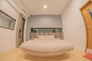 A modern bedroom with a large bed, a built-in window, and a wooden door.