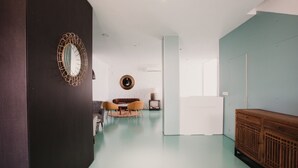 Un interior moderno con un armario de madera, un espejo redondo y una zona de estar con una mesa y sillas.