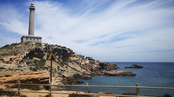 A lighthouse on a rocky hill overlooking a calm sea.