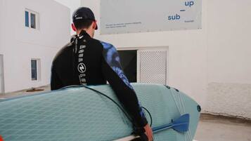 A person sitting on a surfboard in a room with a large poster on the wall.