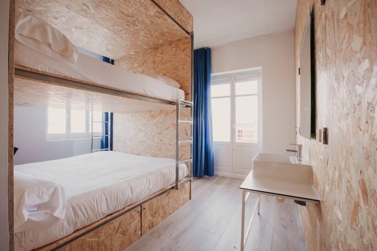 A bunk bed room with a desk and a window.