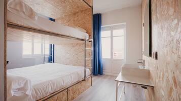 A bunk bed room with a desk and a window.
