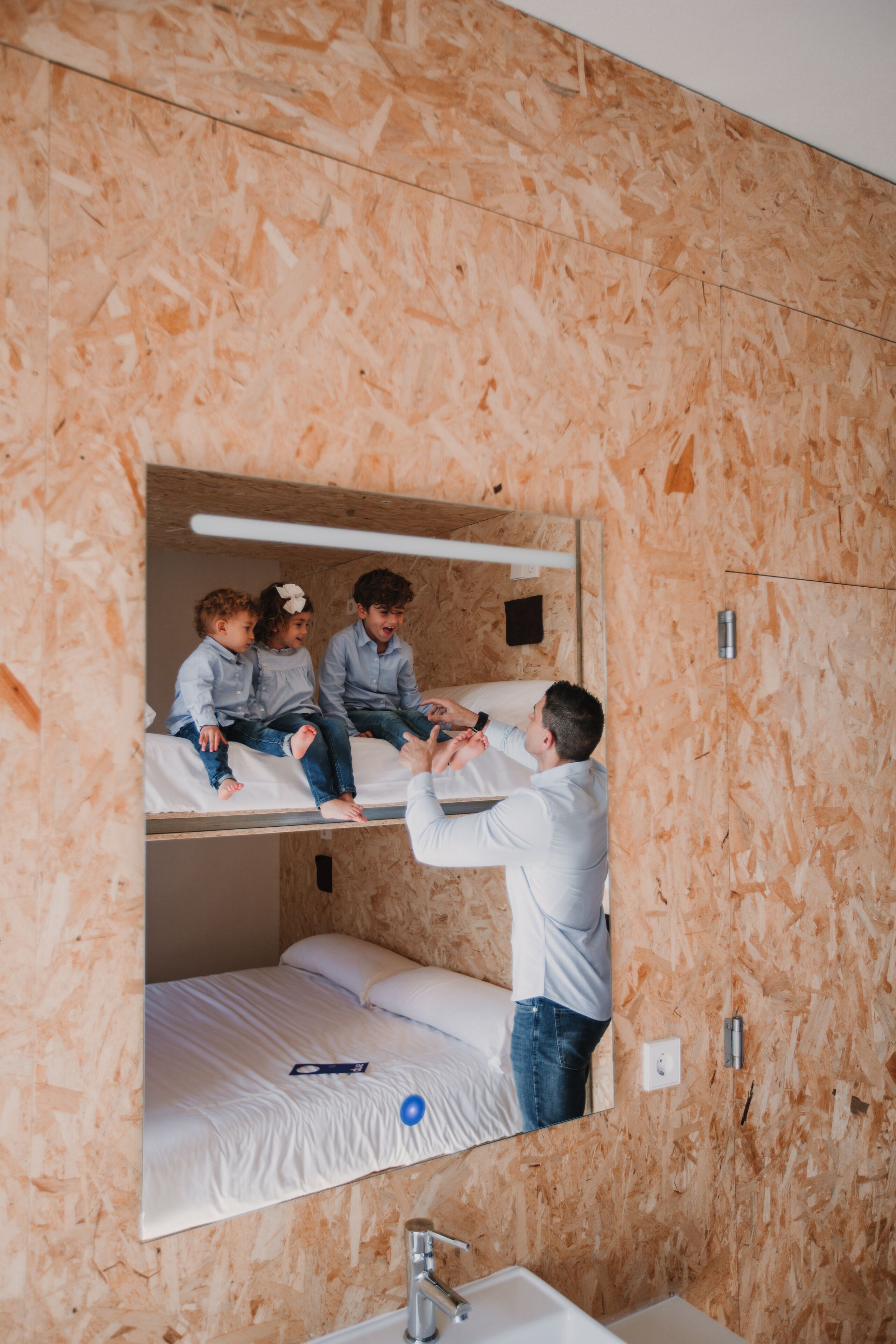 Dormitorio con literas, un espejo, un lavamanos y una ventana pequeña.