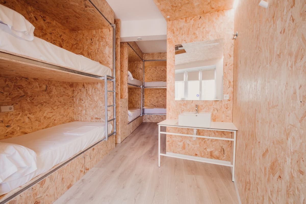 A bunk room with bunk beds, a small sink, and a mirror.