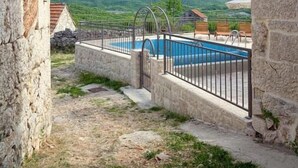 Edificio de piedra con piscina y vistas a colinas verdes.