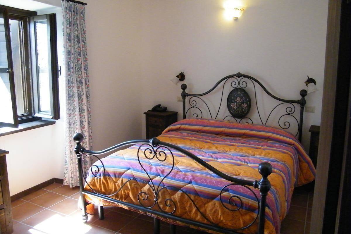 Een slaapkamer met een bed, nachtkastje, lamp en een raam met gordijnen.