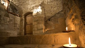A stone interior with a lit candle on a ledge, a wooden door, and a stone bench. - Agriturismo Il Casanova (Baschi)