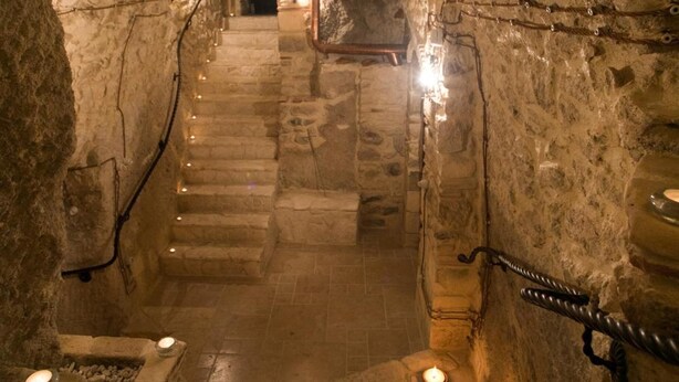 A stone staircase leading to a higher level in a cave-like structure, with candles providing light. - Agriturismo Il Casanova (Baschi)