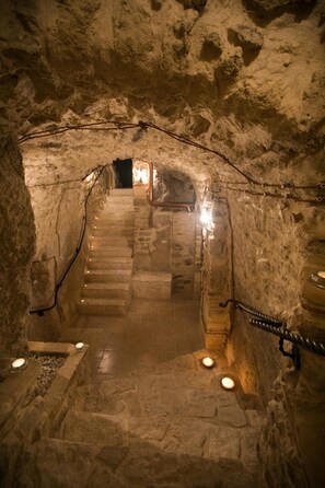 A stone staircase leading to a higher level in a cave-like structure, with candles providing light. - Agriturismo Il Casanova (Baschi)