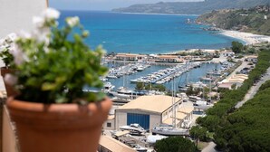 A marina with boats docked, a building with a blue garage, and a coastal view with a beach and hills in the background. - Agriturismo Il Casanova (Baschi)