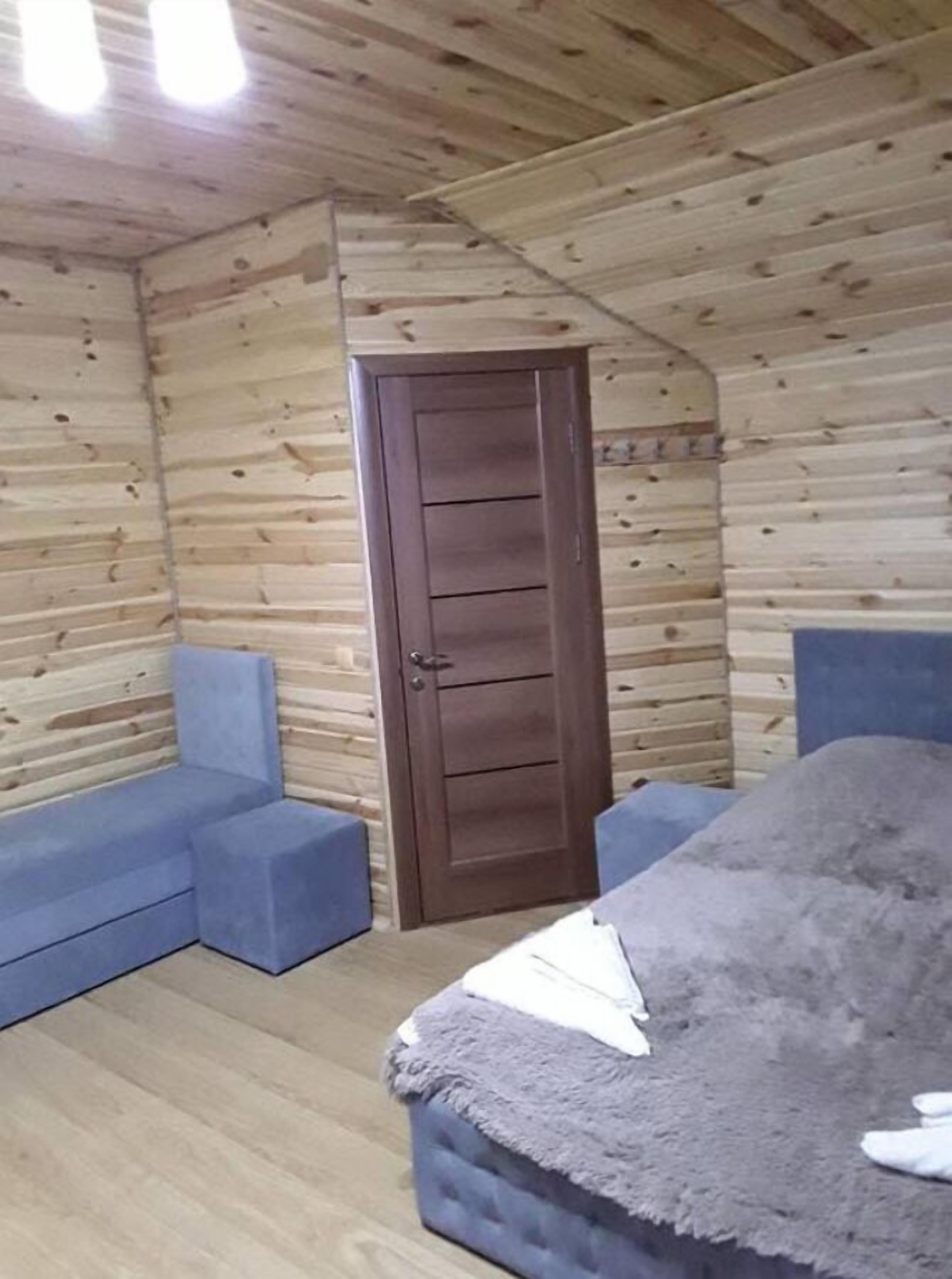 A room with a wooden ceiling, a door, and blue upholstered seating.