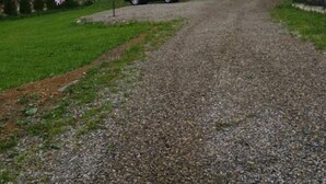 A multi-story building with balconies, a gravel driveway, and a parked car. - Saduba Perluna Bukovel (Bukovel)