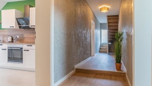 Une cuisine moderne avec des meubles blancs, un plan de travail en bois et une bouilloire en acier inoxydable.