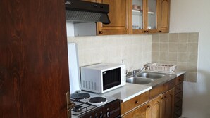 A kitchen with wooden cabinets, a microwave, a stove, and a sink. - Apartments Mirjana (Dugi Rat)