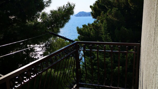 A balcony with a view of a body of water and trees. - Apartments Mirjana (Dugi Rat)