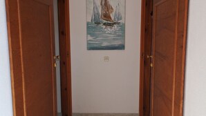 A hallway with wooden doors and a painting of sailboats on the wall. - Apartments Mirjana (Dugi Rat)