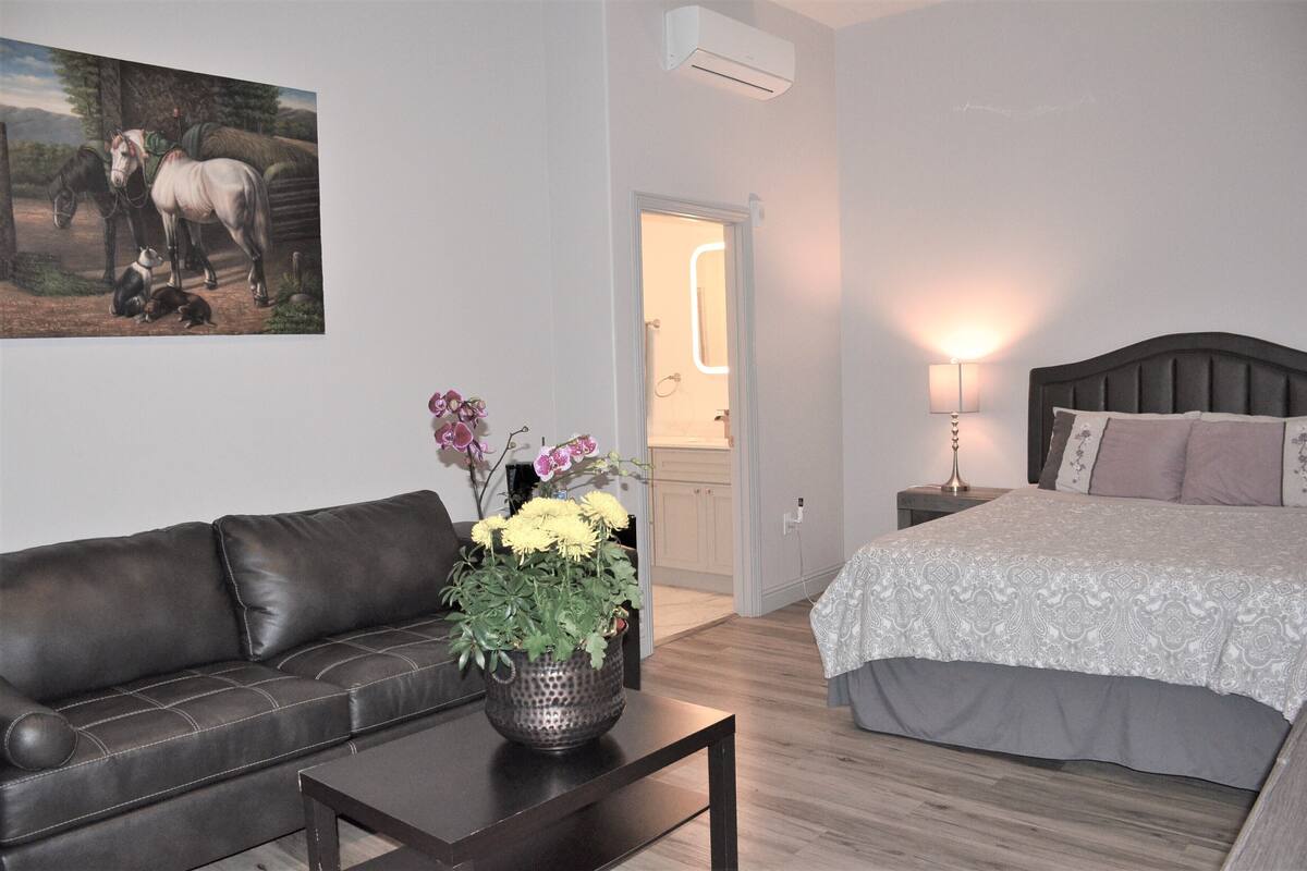 A bedroom with a bed, bedside table, lamp, and a painting on the wall.