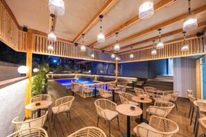 Un espace extérieur aménagé avec des chaises et des tables en osier, une piscine et une terrasse en bois.