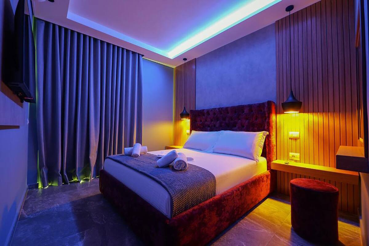 Una habitación de hotel moderna con una cama grande, un televisor de pantalla plana y un cabecero de madera.