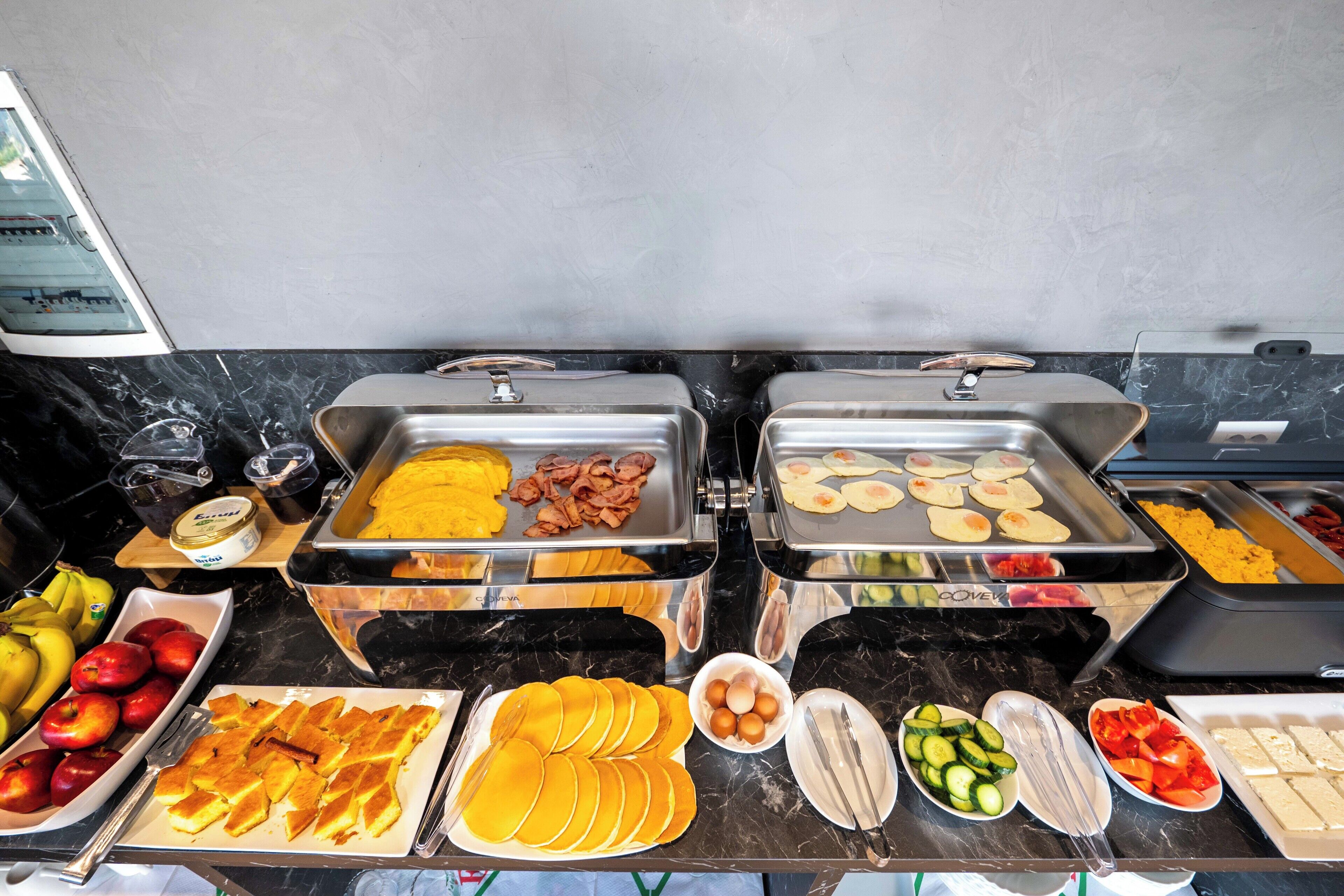 A buffet with various food items including fruits, eggs, and pastries.