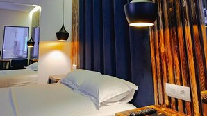 Habitación de hotel con cama, mesita de noche, televisor y una pared con listones de madera verticales.